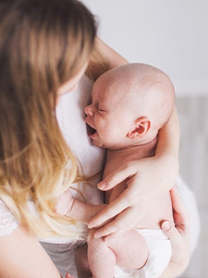 Baby crying in arms of mother