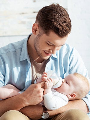 father feeding baby with milk from baby bottle